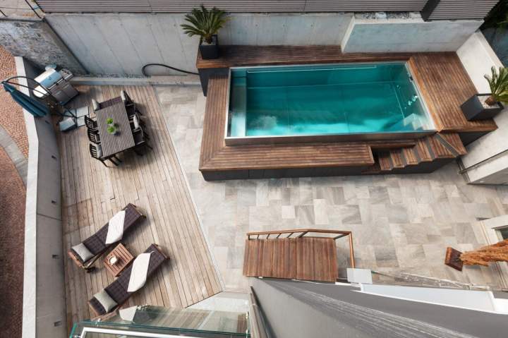 Une terrasse en bois moderne avec des lignes épurées et des plantations intégrées, parfaite pour les repas en extérieur et la détente.
